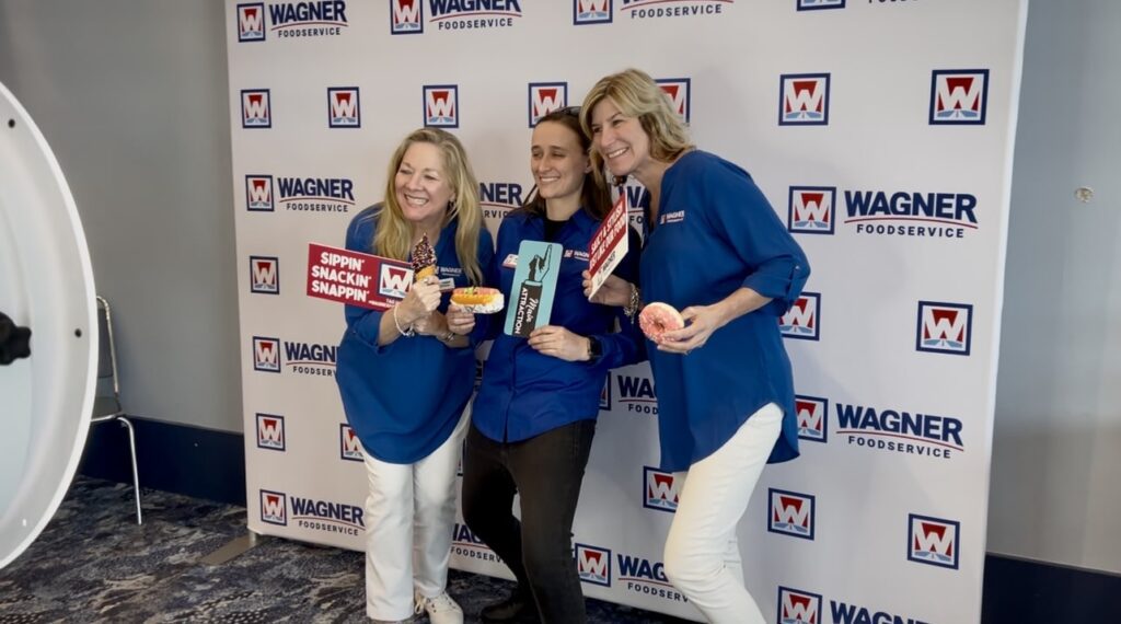 attendees posing in front of branded backdrop