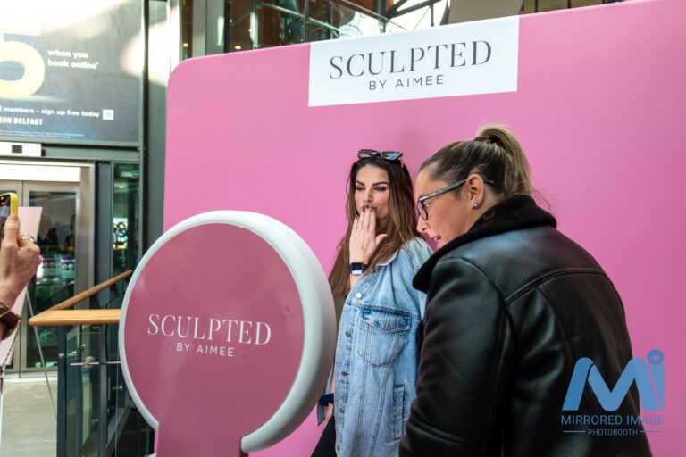 guest posing at branded booth with branded backdrip